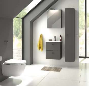 Modern bathroom with grey wall-hung vanity and tall cabinet, white sink and black faucet, yellow towel, slanted skylight and large glass walls with a potted plant.