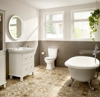 Bright vintage bathroom with white vanity and sink, mirror, tall cabinet, toilet, clawfoot tub, and a hanging plant by the window.