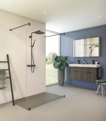 Modern bathroom with glass shower enclosure, black fixtures, blue wall behind a floating vanity, mirror, window view, potted plant, towel ladder.